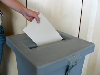 Abgabe der Wahlunterlagen in eine Wahlurne