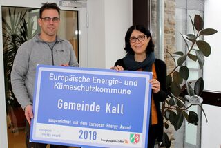 Frau Tehranchi und Herr Feld halten Schild Klimaschutzkommune Gemeinde Kall