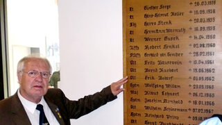 Dieter Züll, der die Gedenkfeier am 2. Oktober mit organisiert, beim Nörvenicher Jabo-Geschwader Boelcke vor der Tafel mit den Namen der bei Abstürzen getöteten Piloten. Auch der Name von Erik-Edgar Bedarf ist dort aufgeführt.