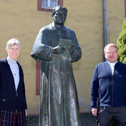 Pater Lambertus Schildt und Schwester Helene Engelmayer neben der Statue von Pater Jordan vor dem alten Gästehaus in Steinfeld.
