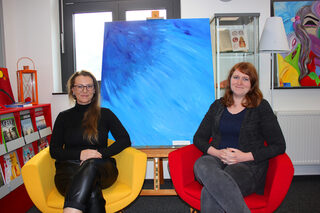 Magdalena Konkel (links) mit Bibliotheksleiterin Michelle Wagner vor einem der Werke der Künstlerin, die in der Bibliothek ausgestellt sind.