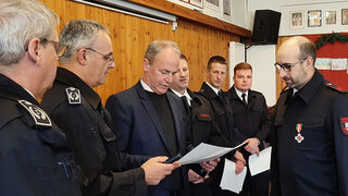 Bürgermeister Hermann-Josef Esser verliest die Urkunde zur Verleihung des silbernen Feuerwehrehrenzeichens an Rainer Latz (rechts).