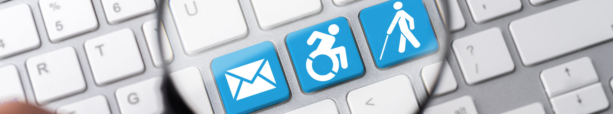 Auf einer Tastatur werden durch eine Lupe verschiedene Symbole für Behinderungen angeschaut